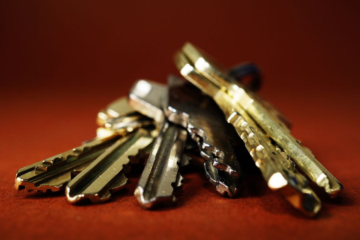 A pile of brass keys of different profiles on a red surface