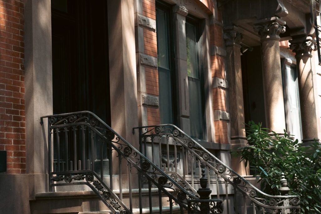 Brick apartment building entrance with a stoop and iron railings in New York