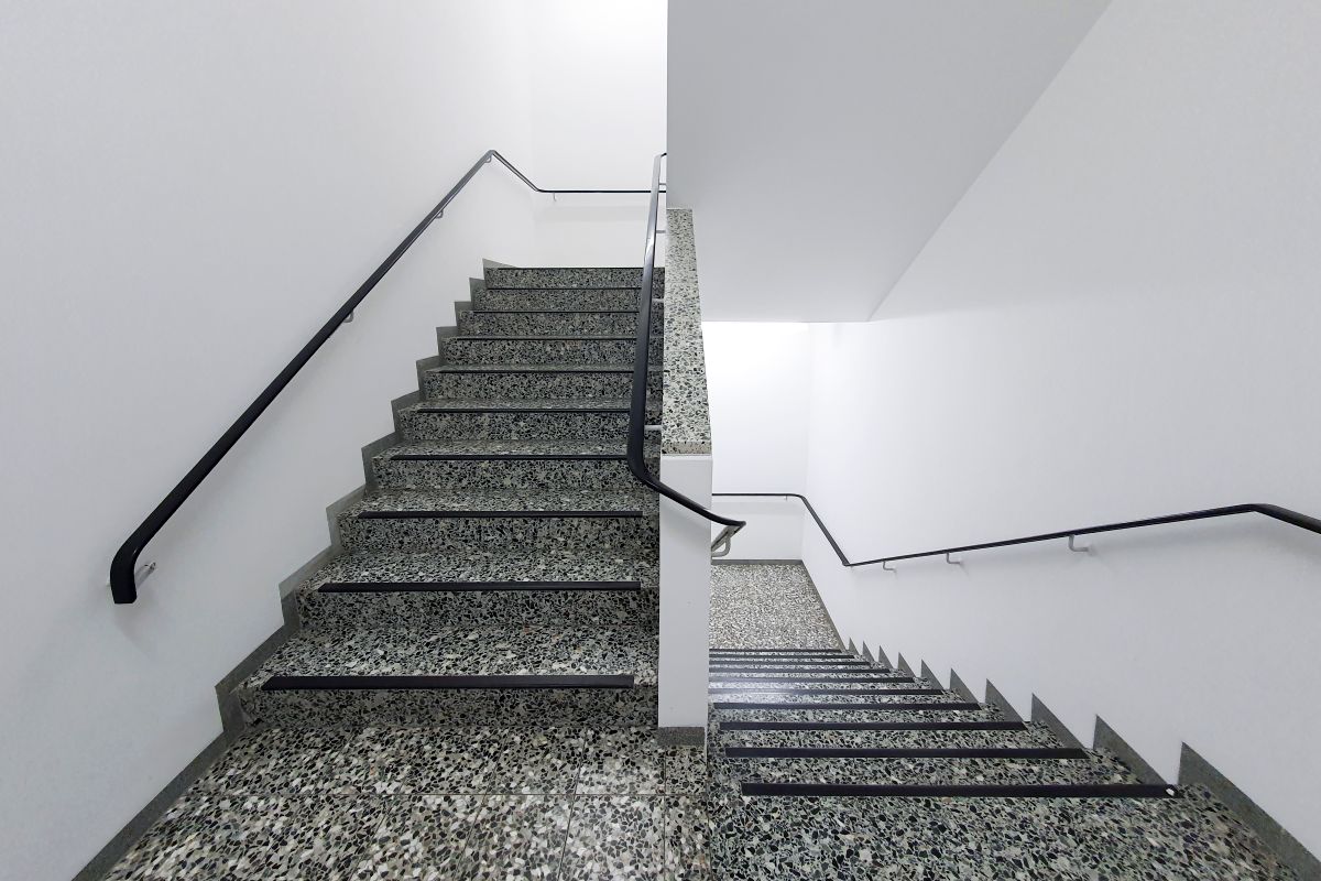 Interior stairwell with terrazzo steps and steel handrails in an apartment building