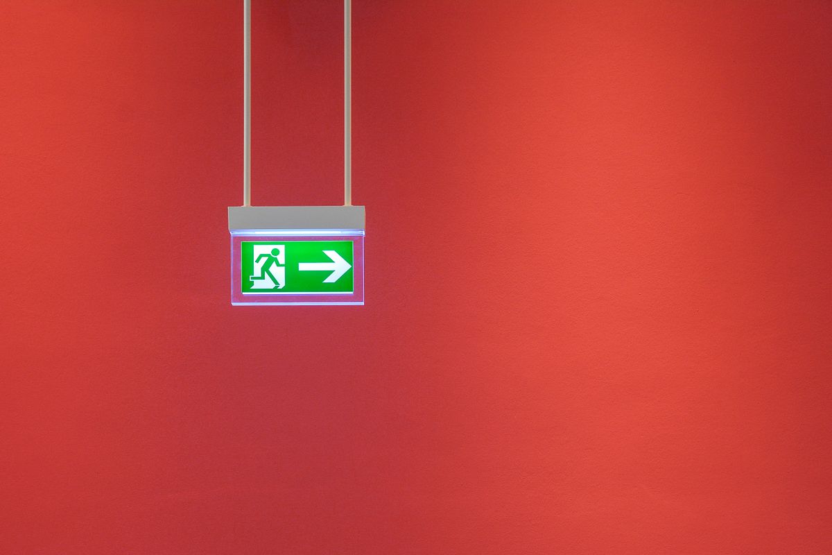 Illuminated green exit sign hanging from a ceiling