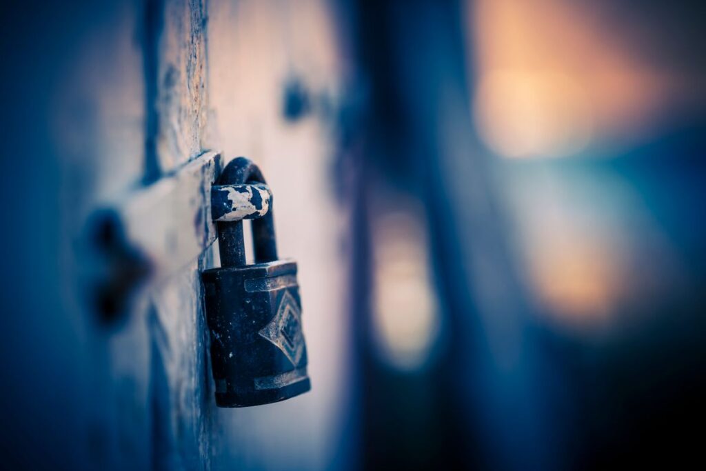 An old padlock securing a weathered gate, evoking disciplined key control