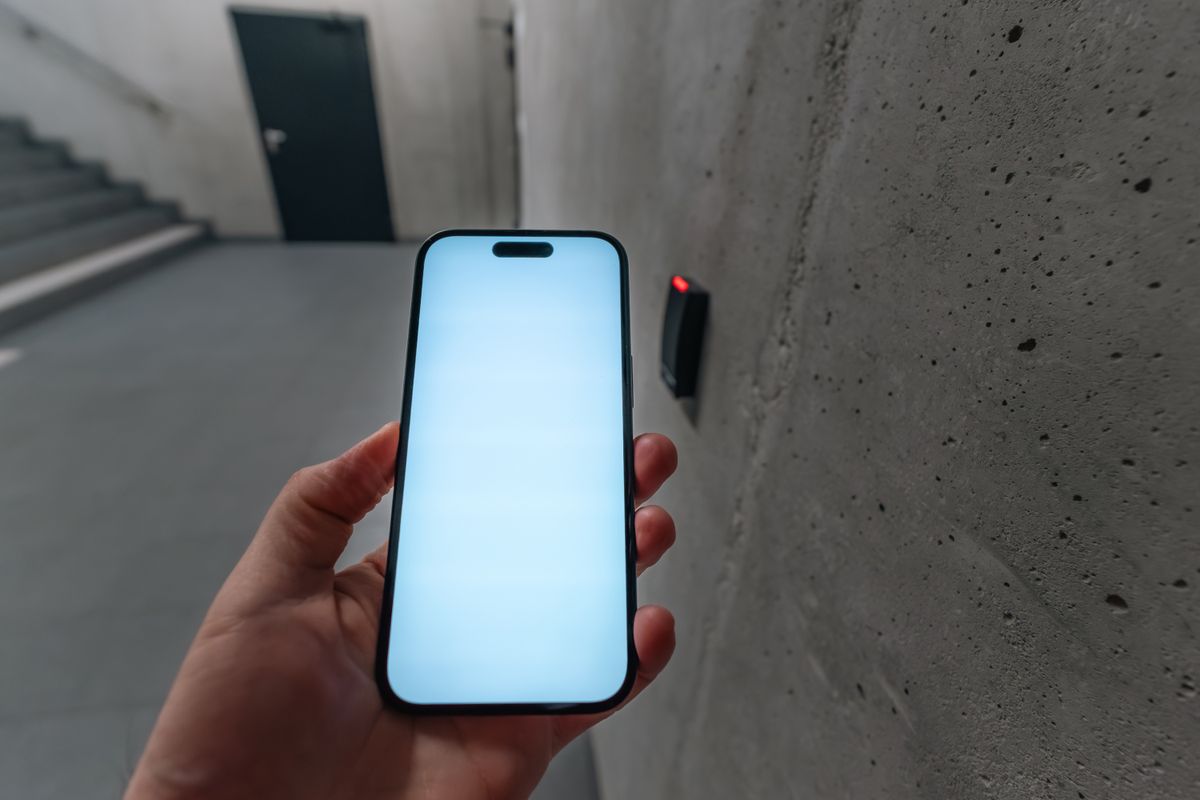 Resident holding a phone at a building door with an electronic reader