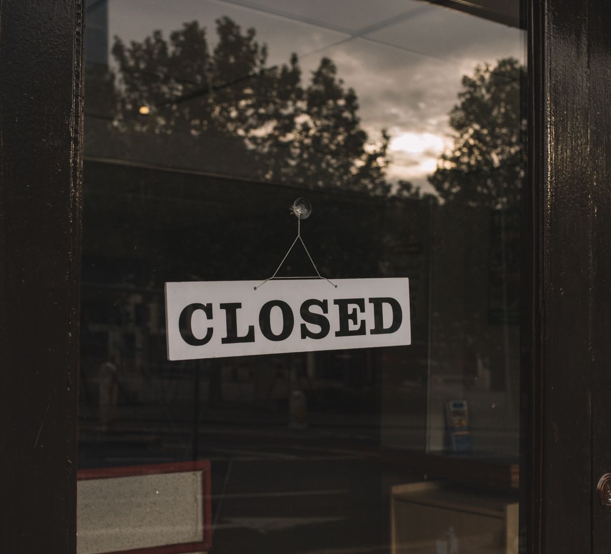 Closed sign hanging on a storefront glass door