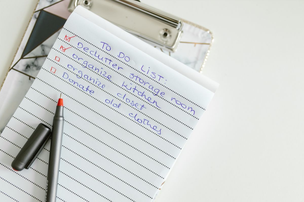 Handwritten to-do checklist on a clipboard with a pen