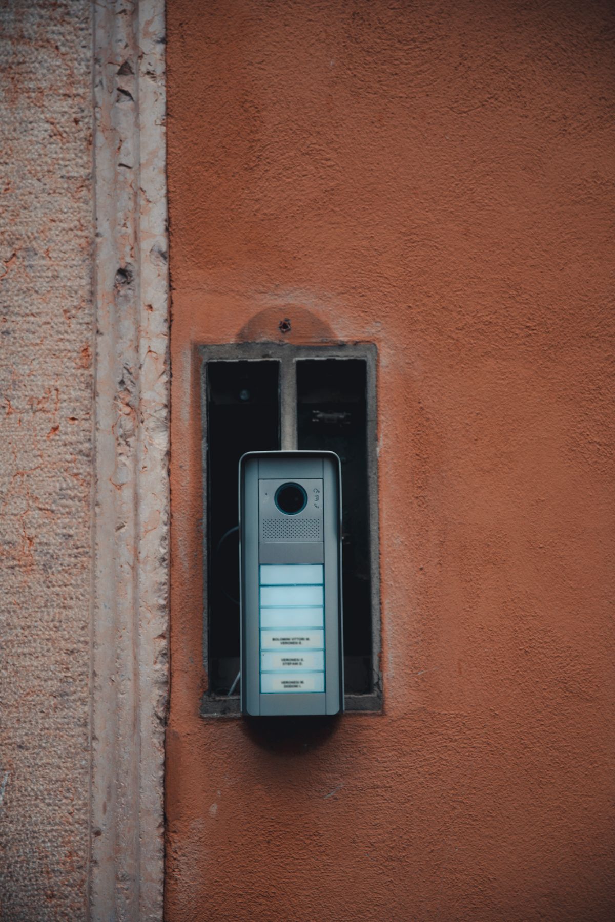 Modern video intercom panel retrofitted into the recess of an older wall station