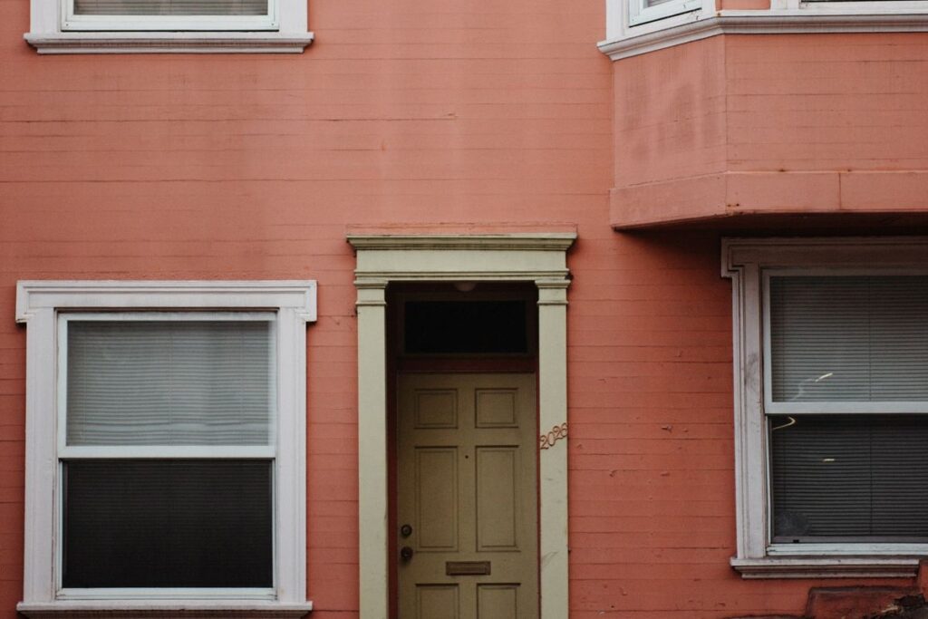 Wooden front door of a rowhouse-style building in bright daylight